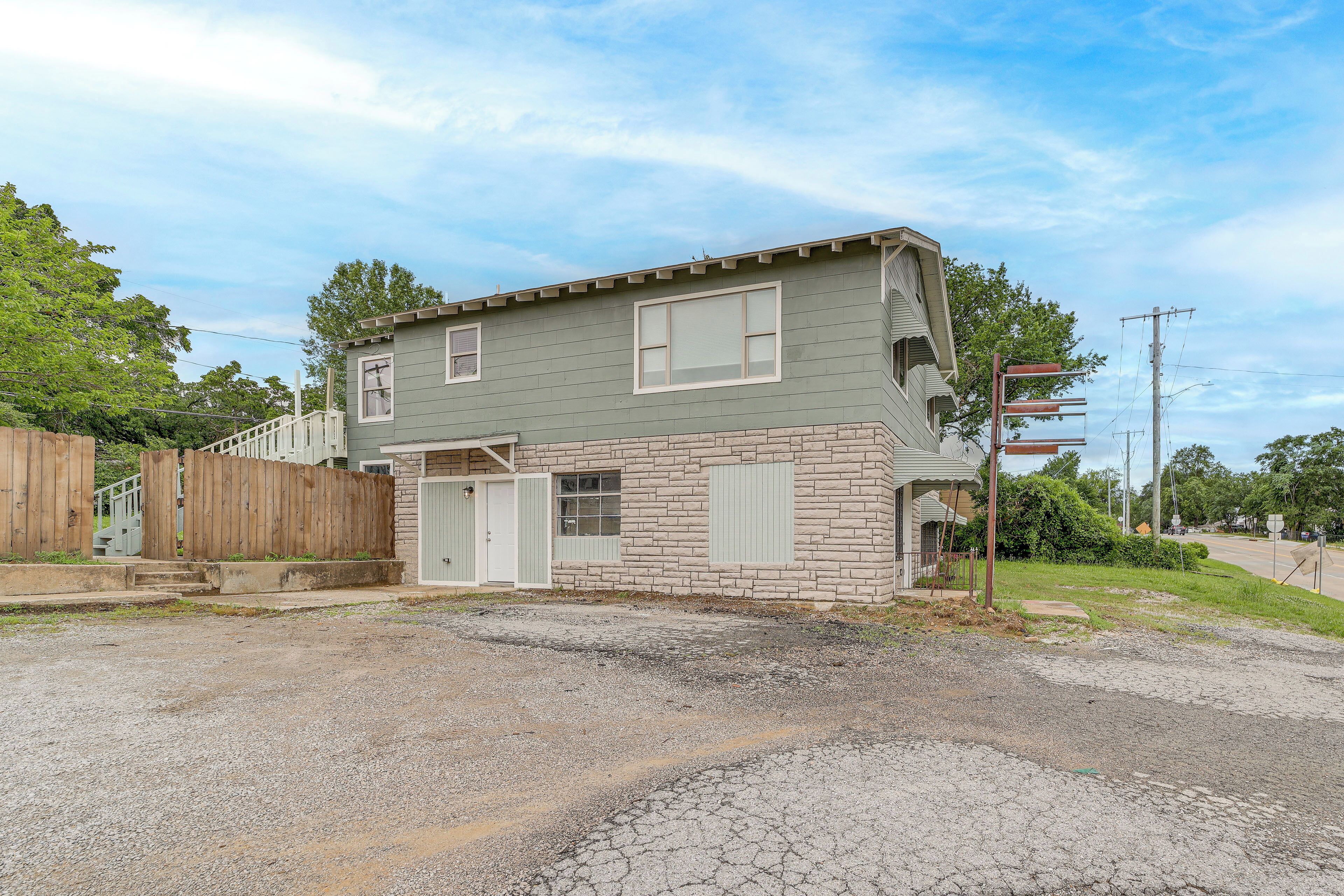 A two-story house with a garage, a wooden fence, and a gravel driveway.