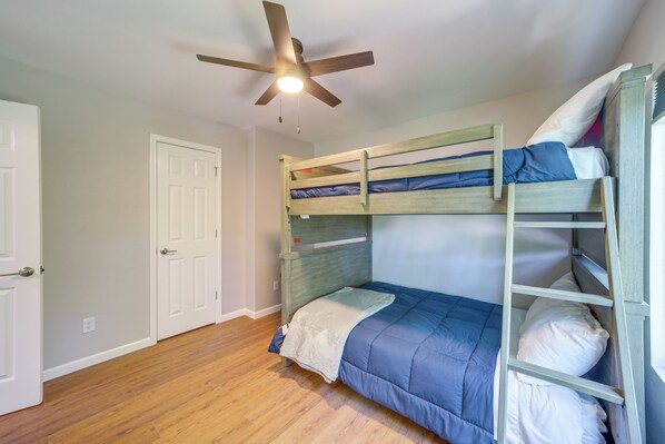 A bunk bed with a ladder, a ceiling fan, and a white door in a room with wooden flooring. - 7 Mi to Dtwn: Authentic Haunted Apt in Tulsa! (Tulsa)