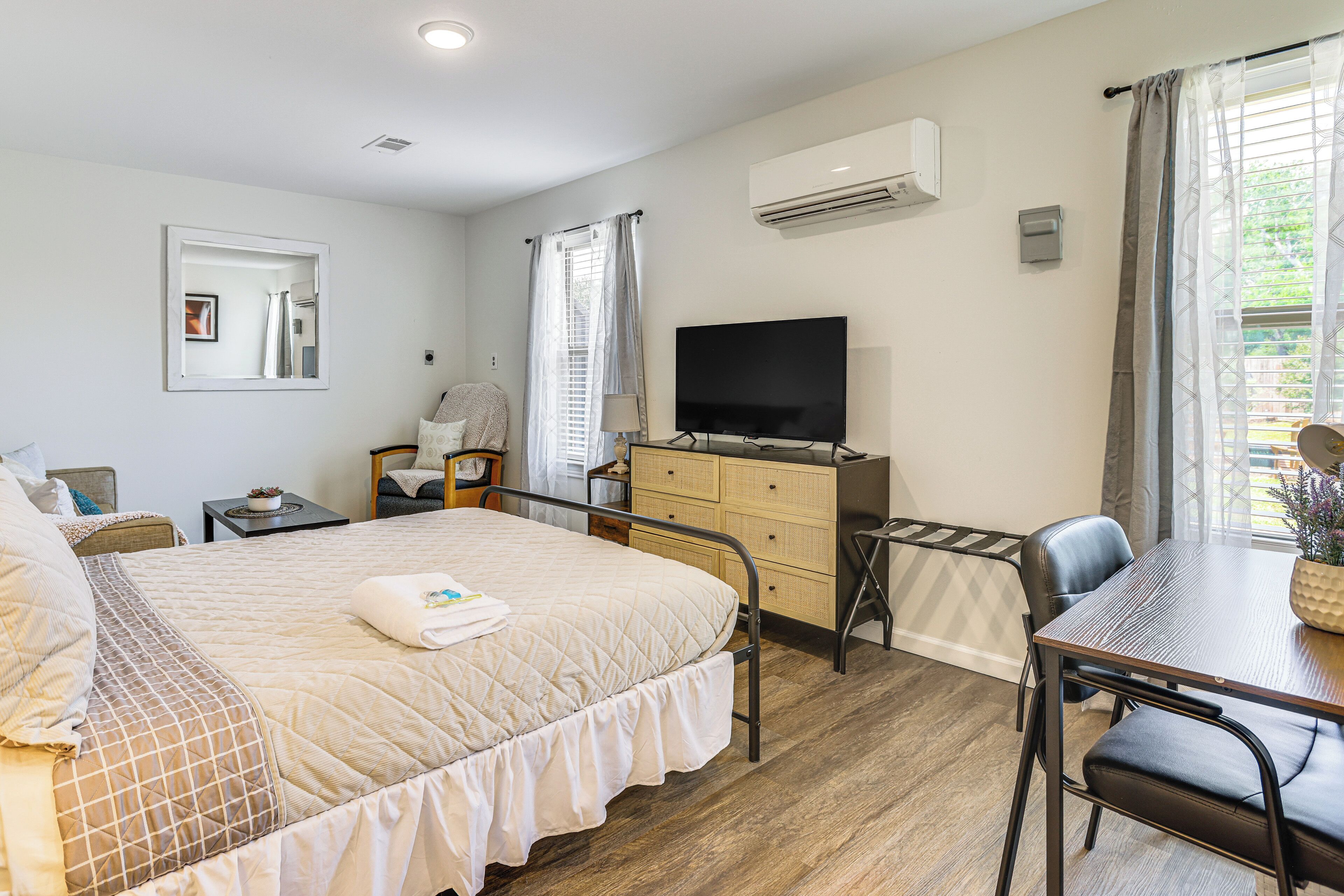 A bedroom with a bed, a TV, a desk, and a chair.