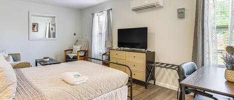 A bedroom with a bed, a TV, a desk, and a chair.