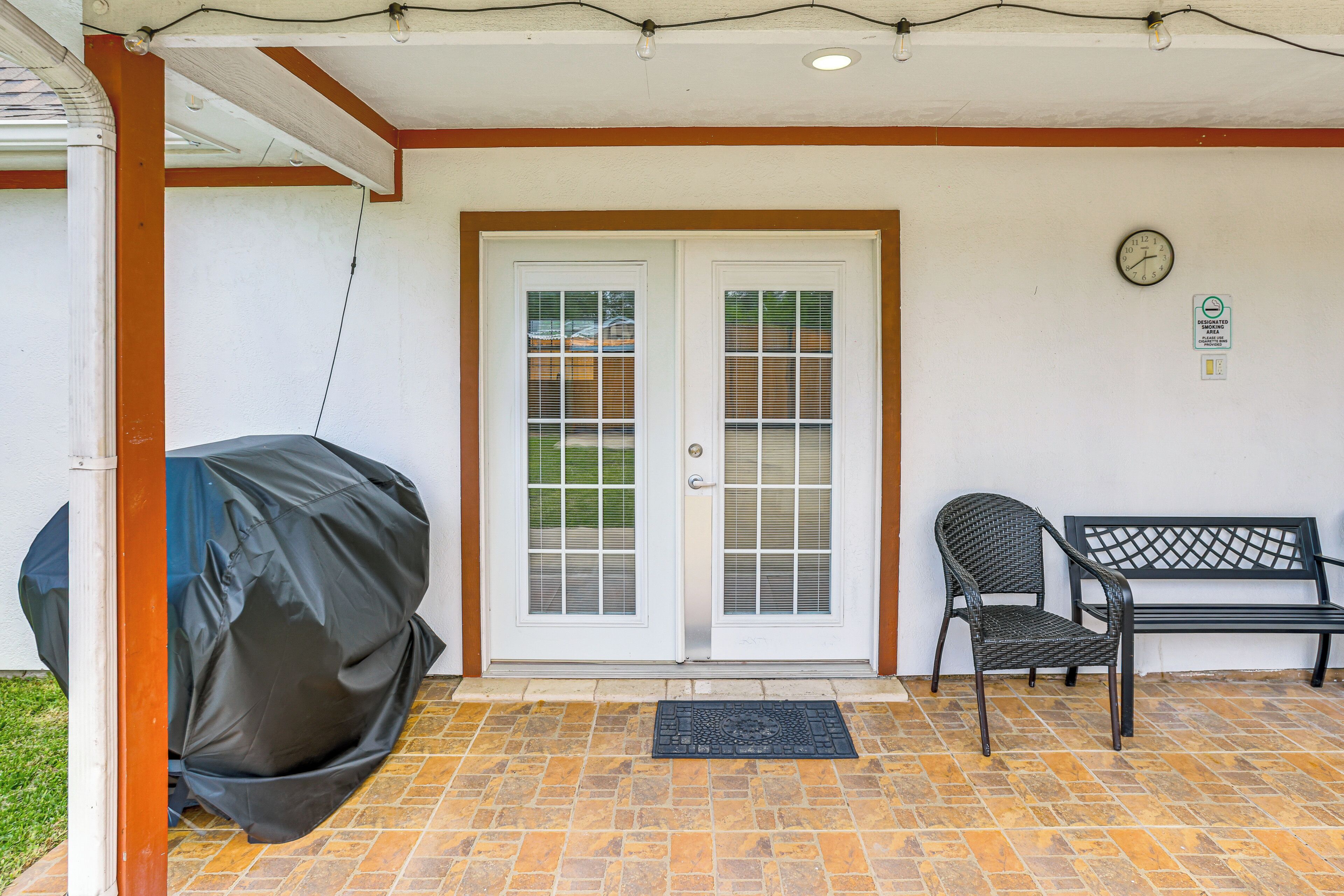 A covered patio with a grill, a bench, and a door with glass panels.