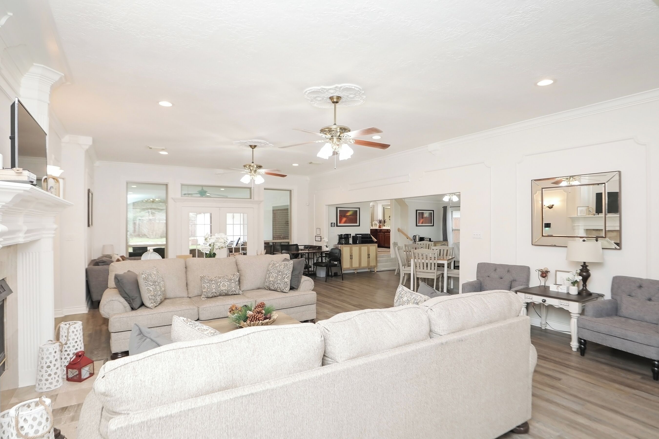 A spacious living room with a fireplace, a dining area, and a kitchen in the background.
