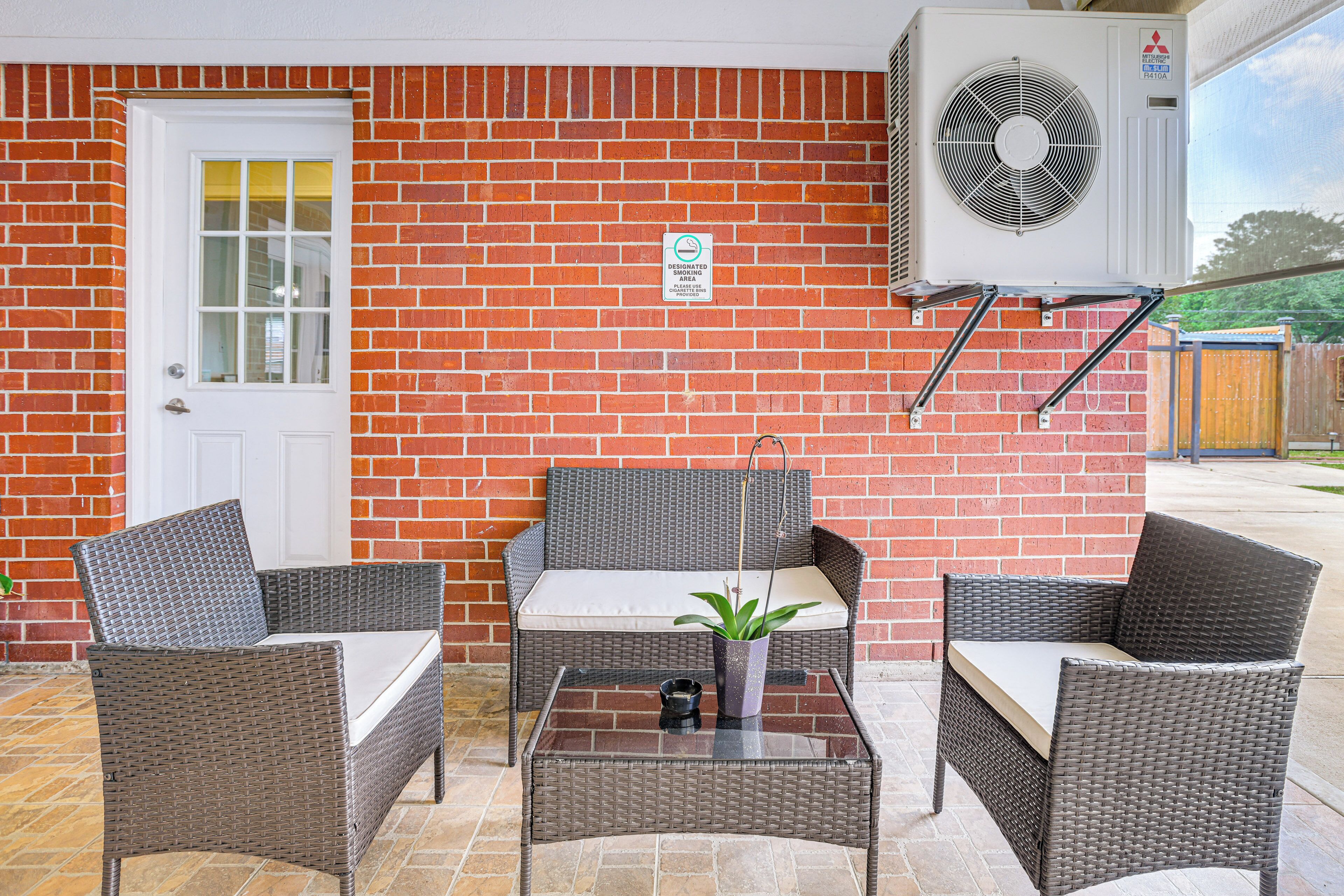 A patio area with wicker furniture, a small table, and a potted plant.