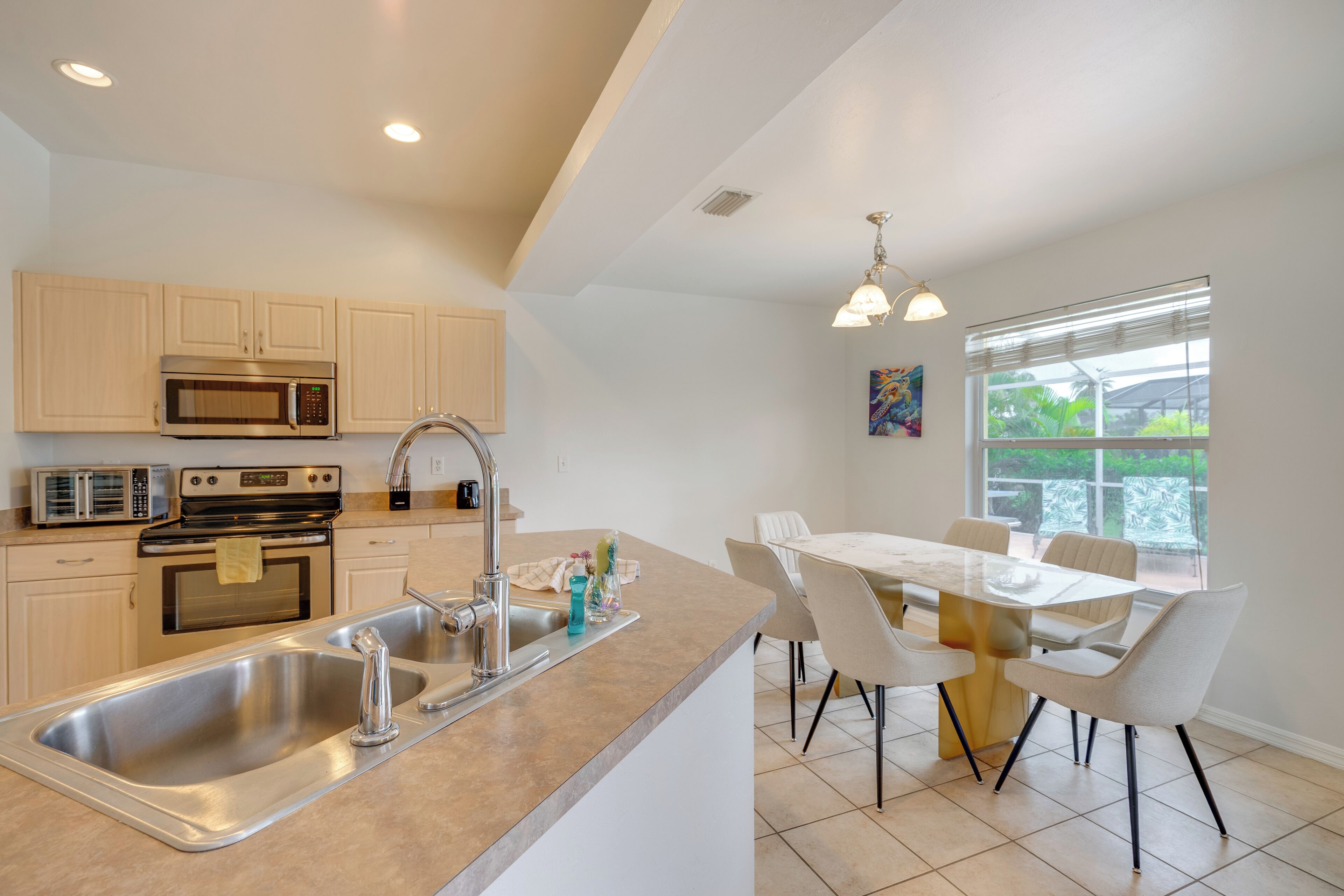 A modern kitchen with stainless steel appliances, a double sink, and a dining area with a table and chairs.