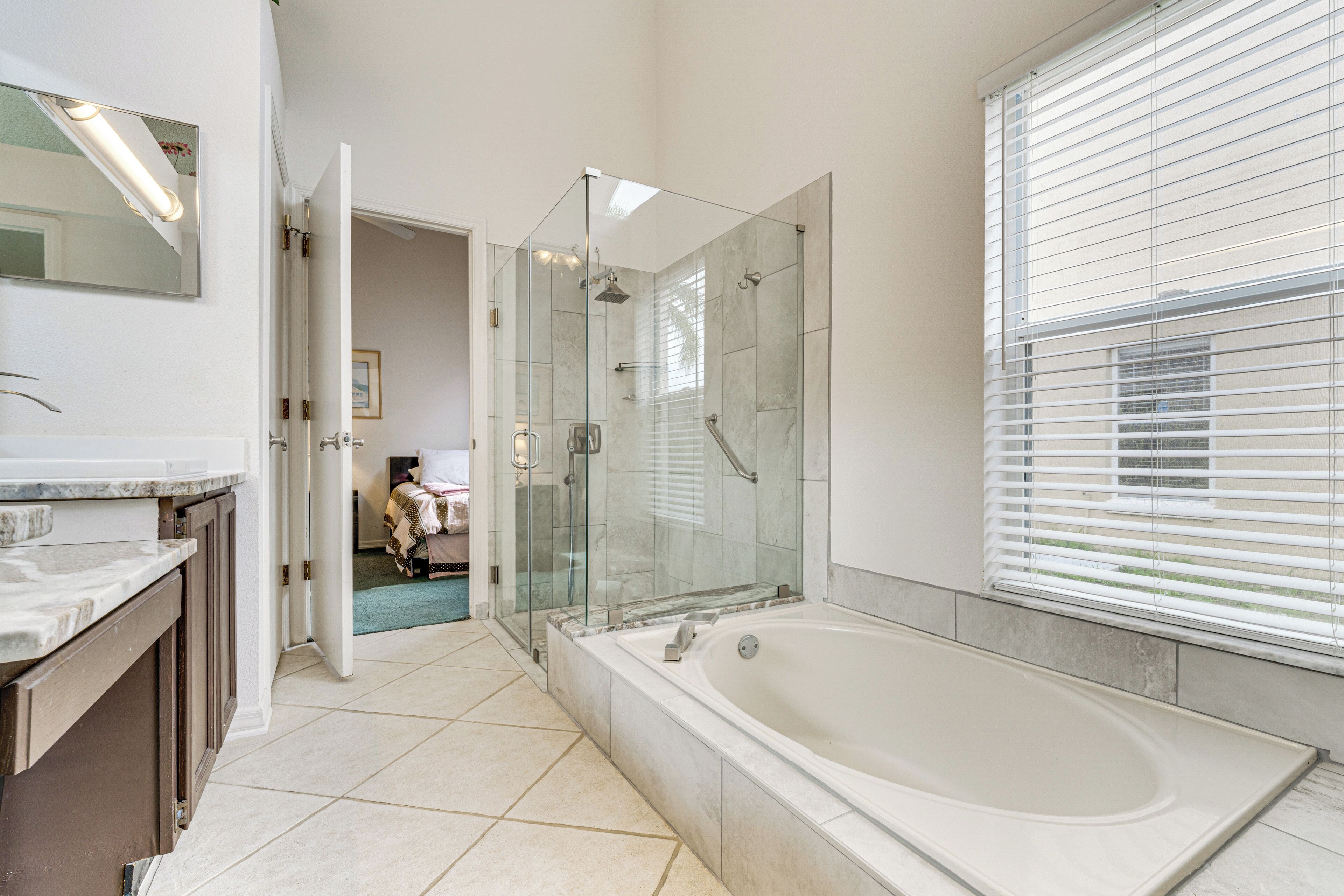 A modern bathroom with a glass-enclosed shower, a large bathtub, and a vanity with a mirror.