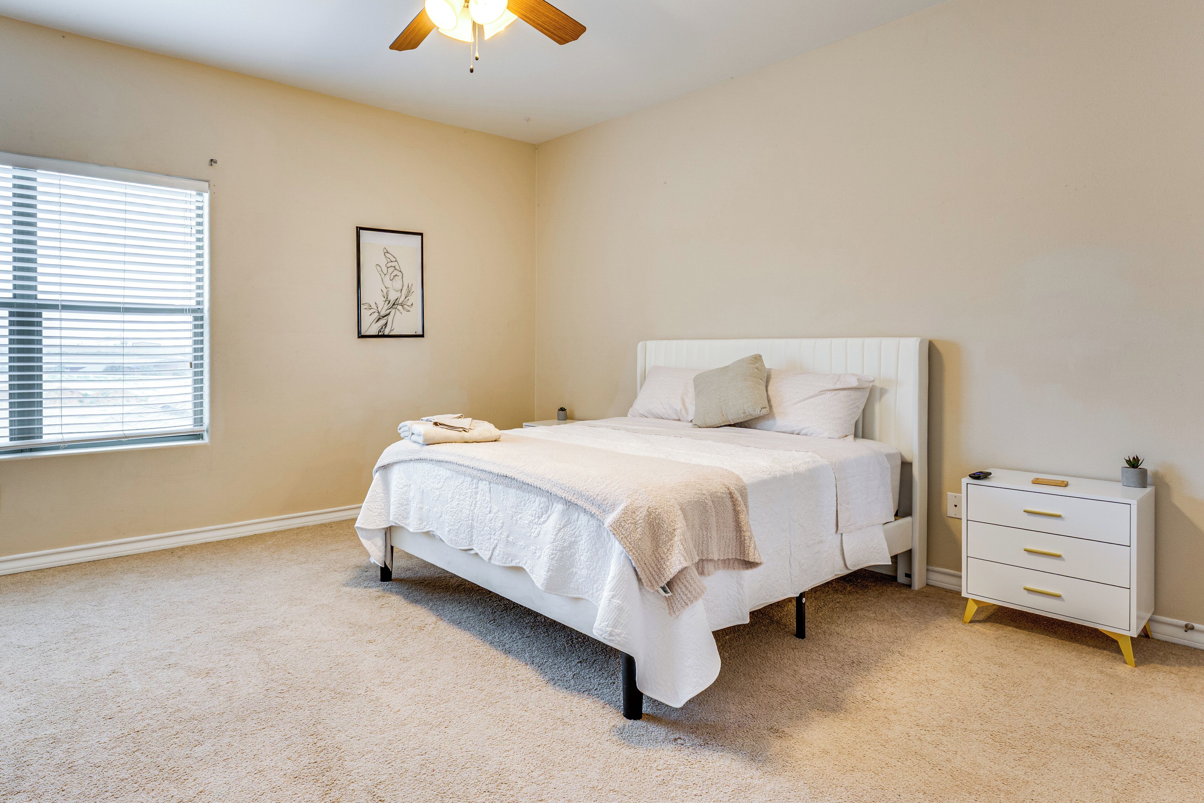 A bedroom with a bed, bedside table, and a window with blinds.
