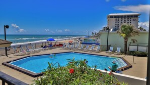 Ein Poolbereich mit Liegestühlen und Blick auf den Strand.
