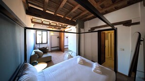 Une chambre à coucher comprenant un lit, un canapé, un plafond en bois et une porte donnant sur une salle de bain.