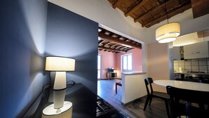 Une cuisine moderne avec un coin repas, comprenant un plan de travail noir, une lampe et une vue sur le salon.