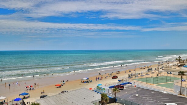 A beach with a tennis court and a lifeguard tower.