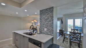 A modern kitchen with a built-in dishwasher, a large island with a sink, and a stone backsplash.