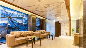 A modern lobby with a large window, a sectional sofa, a coffee table, and a reception desk.