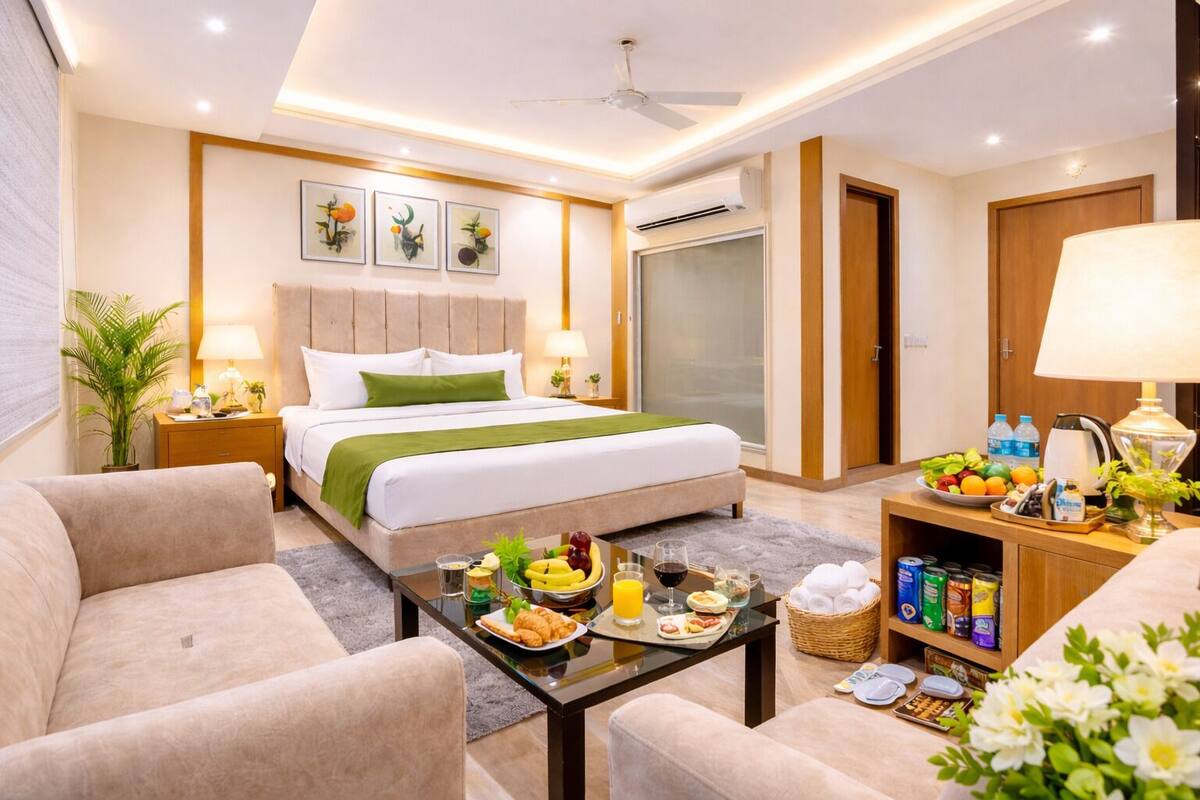 Una camera d'albergo con un letto, comodini, un tavolino, un divano e un'area da pranzo con prodotti per la colazione.