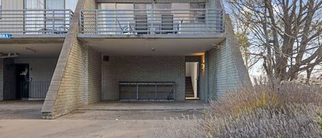 A two-story building with a balcony, a brick wall, and a metal gate.