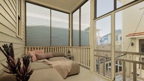 En balkon med polstrede siddepladser, et lille bord med en lygte og en potteplante.