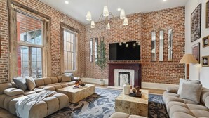 Una sala de estar con pared de ladrillo, ventanas amplias, chimenea y televisor de pantalla plana.