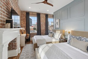 Une chambre d’hôtel avec deux lits, une cheminée, un bureau et une vue sur la ville.