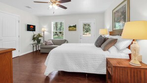 A bedroom with a bed, a ceiling fan, a TV, a plant, and a door with a view of the outdoors. - Clare House I Couples, Stargazing (San Marcos)
