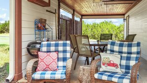 A covered porch with wicker furniture, a grill, and a view of the outdoors. - Clare House I Couples, Stargazing (San Marcos)
