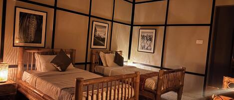 A room with a bed, two chairs, a bedside table, and wall-mounted artwork.
