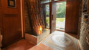 A hallway with a stone wall, a wooden door, and a glass partition.
