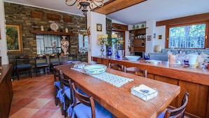 A spacious kitchen with a large wooden table, chairs, and a stone wall.