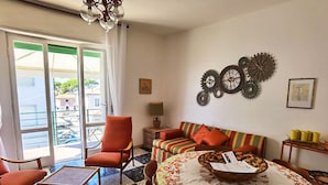 A living room with a sofa, chairs, a table, and a view through a glass door.