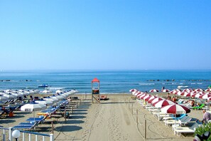 A beach with rows of sun umbrellas and lounge chairs, a lifeguard tower, and the ocean in the background. - Appartamento Anna 100 m dal Mare (Castiglione della Pescaia)