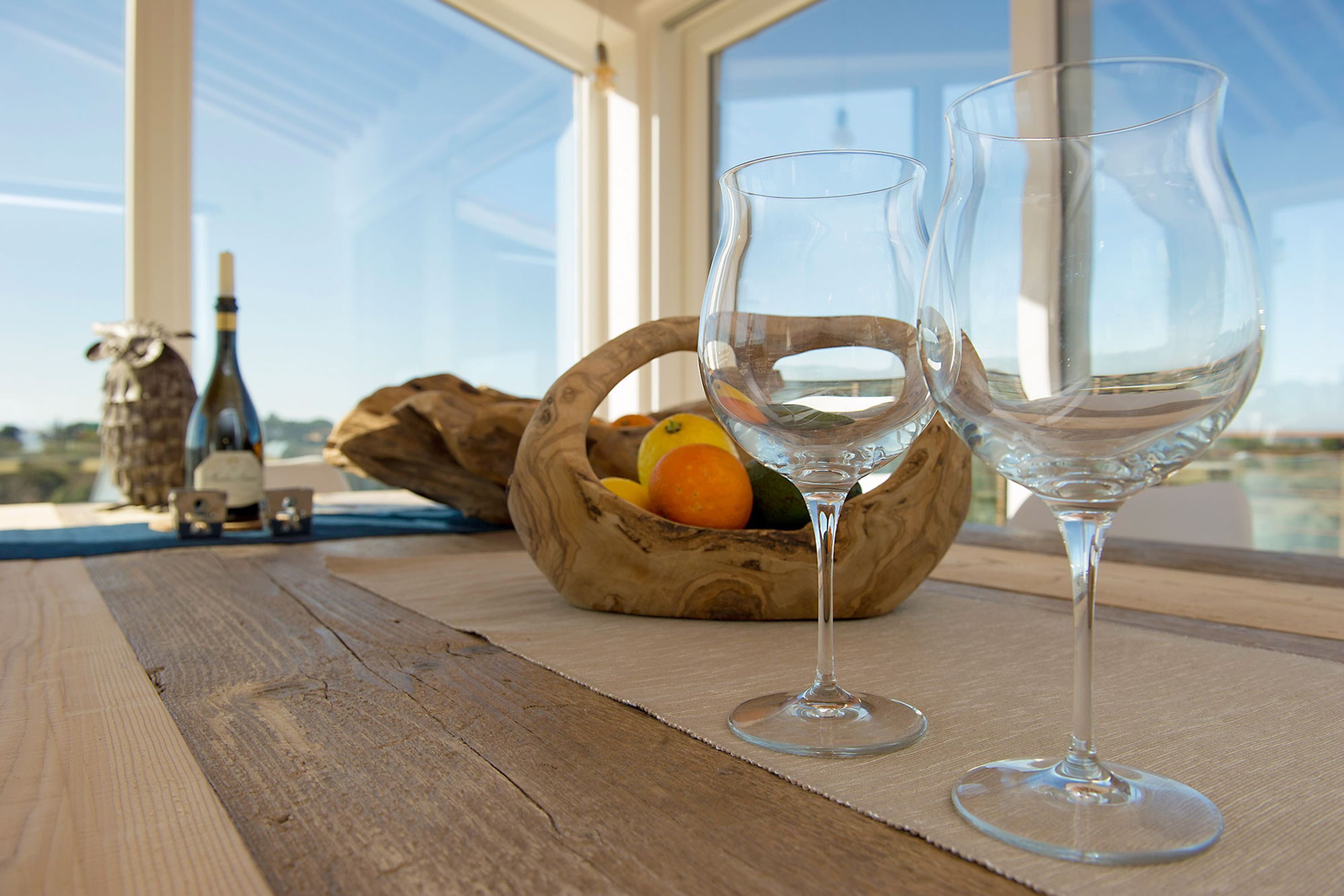 Ein Holztisch mit zwei Weingläsern und einer Fruchtkorb.