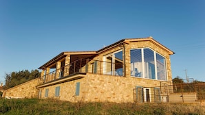 A stone house with a large window and a balcony. - Villa Bibbona con Piscina (Bibbona)