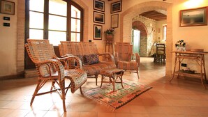 A cozy living room with wicker furniture, a patterned rug, and a dining area with a table and chairs. - Villa Este con Piscina (Civitella Paganico)