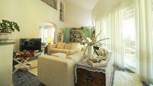 A living room with a sofa, a television, a bookshelf, and a potted plant. - Villa Gio-d con Grande Giardino (Grosseto)