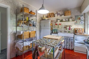 Une cuisine avec des étagères en métal, un réfrigérateur et divers ustensiles de cuisine.