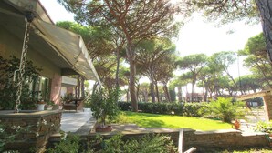 A courtyard with a stone bench, potted plants, and a lawn. - Villa Gio-d con Grande Giardino (Grosseto)