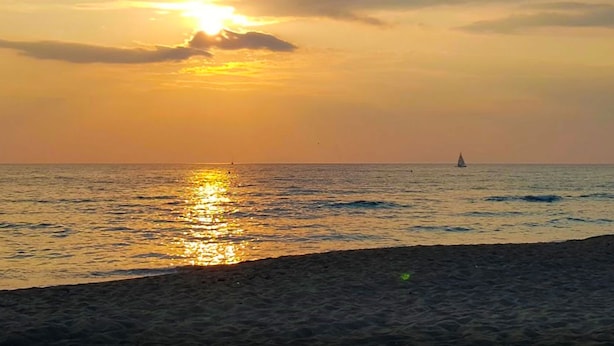 A sunset over the ocean with a sailboat in the distance. - Villa Gio-d con Grande Giardino (Grosseto)