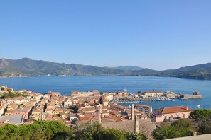 Une ville côtière dotée de bâtiments historiques, d’un port de plaisance et bordée de montagnes.
