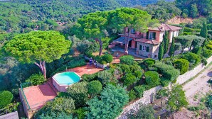 A villa with a swimming pool, surrounded by lush greenery and mountains.