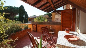 An outdoor patio with wooden chairs, a table, and a terracotta bowl. - Appartamento Le Cannucce al Mare di Castiglione (Castiglione della Pescaia)