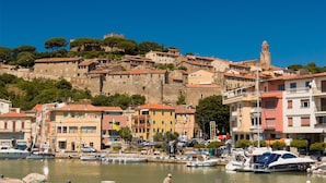 A coastal town with historic buildings, a prominent tower, and a marina with boats. - Appartamento Le Cannucce al Mare di Castiglione (Castiglione della Pescaia)