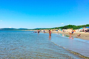 A beach with clear water, people, and umbrellas.
