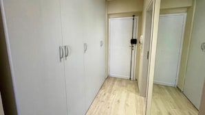 Un couloir doté d’un plancher en bois, de portes blanches et d’une armoire blanche avec des poignées argentées.