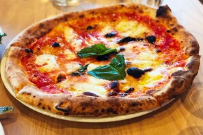 Une pizza à la pâte épaisse, garnie de fromage, de sauce tomate et de feuilles de basilic.