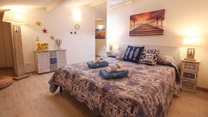 Ein Schlafzimmer mit Bett, Nachttischen, einer Lampe, einem Kleiderschrank, einem Spiegel und einem Wandbild.