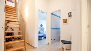 Ein Flur mit einer Holztreppe, einem Spielbereich für Kinder und einem Bett im Hintergrund.