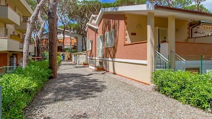 A pathway leading to a building with a covered entrance, surrounded by greenery and trees. - Appartamento Ancora al Mare (Grosseto)