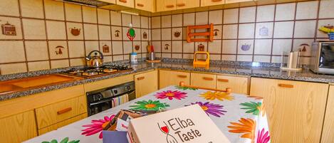 A kitchen with wooden cabinets, a gas stove, and a table with a floral tablecloth.