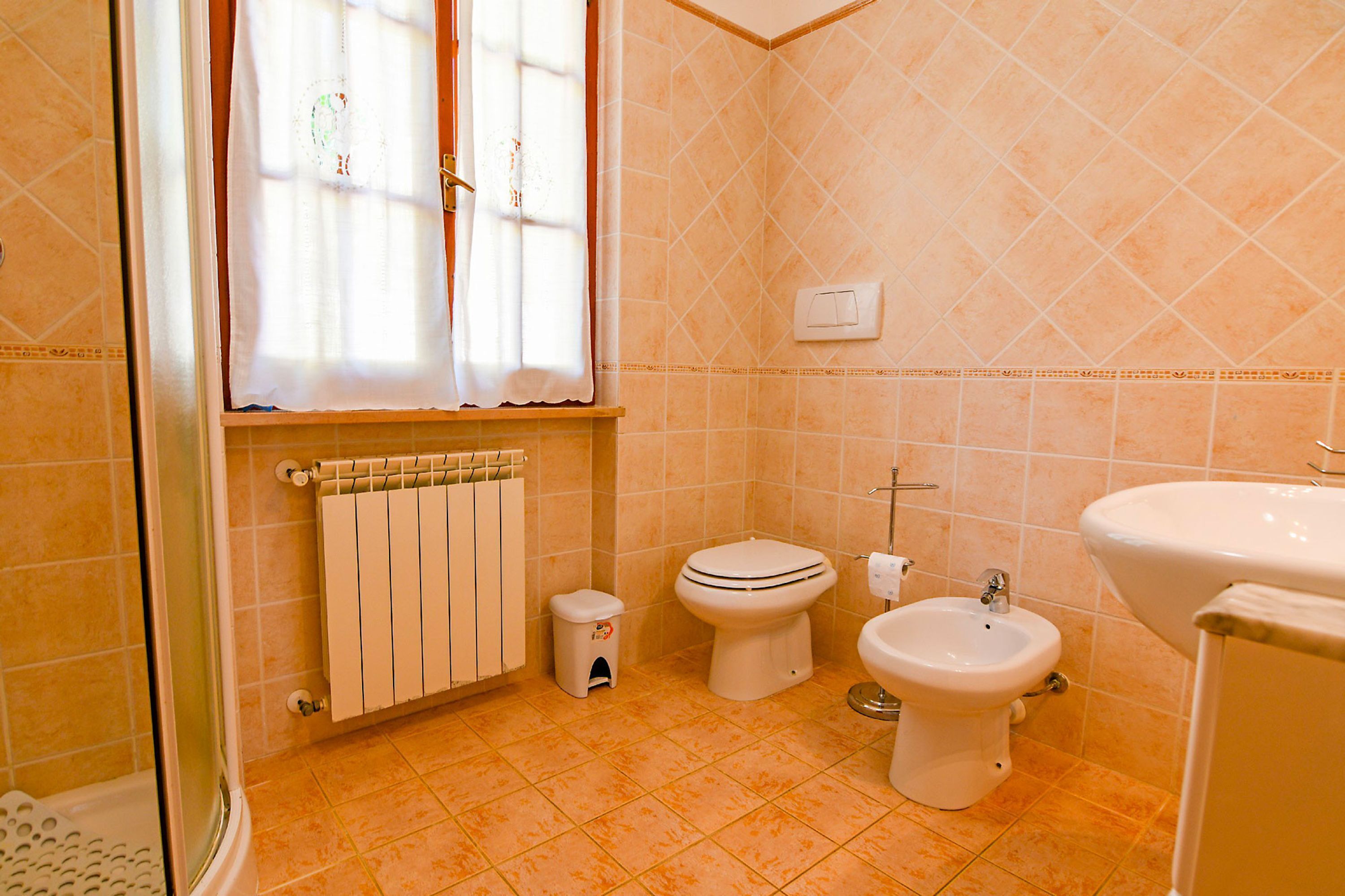 Une salle de bain équipée de toilettes, d’un bidet, d’un radiateur et d’un lavabo.