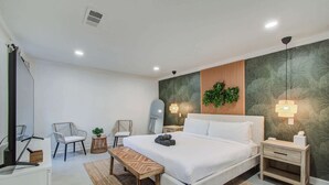 Ein modernes Schlafzimmer mit einem großen Bett, zwei Nachttischen, einer Bank und zwei Stühlen.