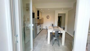 A modern kitchen with a dining area, featuring a large table, chairs, and a refrigerator. - Appartamento Malibu Vicino Alla Spiaggia (Grosseto)