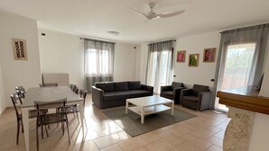 A living room with a dining table, chairs, a sofa, a coffee table, and a ceiling fan. - Villa Kadal a 100 Metri dal Mare (Grosseto)